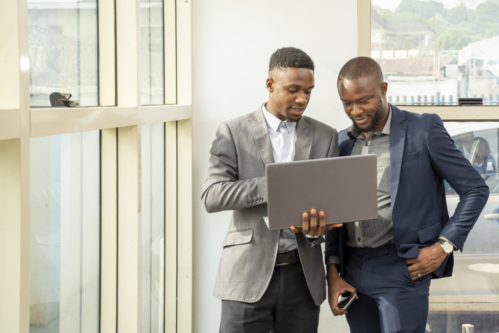 young black businessmen standing together holding a laptop, discussing business